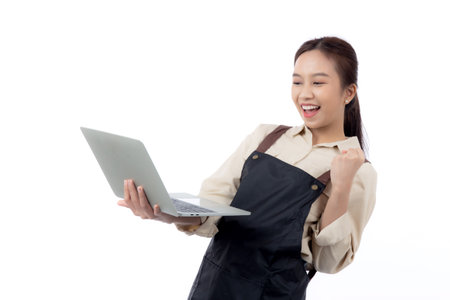 Portrait young asian business woman wearing apron holding laptop computer isolated white background, waitress or barista holding laptop computer with success, cut out, business or freelance.の写真素材