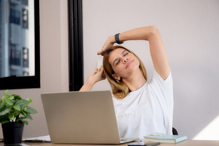 Portrait young caucasian businesswoman taking a break after overworked with stretching arm and hand in living room at home office, business woman relax with ergonomic, business and health.の写真素材