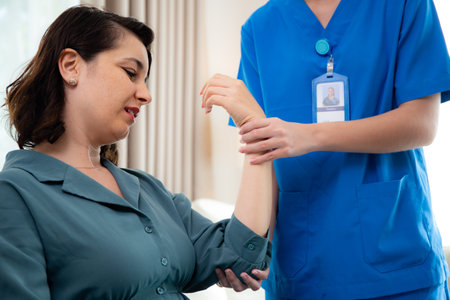 Young nurse therapy with patient while stretching muscle hand in living room at home, doctor woman support and rehabilitation with patient, caregiver and service with woman, medical and rheumatism.の写真素材
