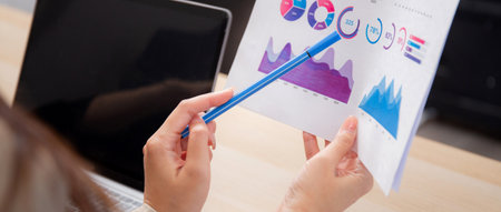 Closeup two businesswoman reviewing financial graphs and charts in modern office, two business woman meeting analyzing and planning statistics finance of marketing, business and investment.の写真素材