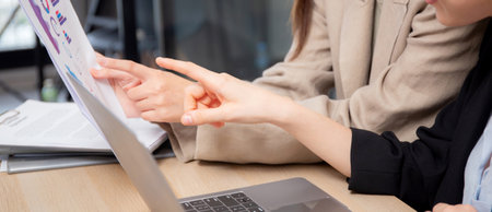 Closeup two businesswoman reviewing financial graphs and charts in modern office, two business woman meeting analyzing and planning statistics finance of marketing, business and investment.の写真素材