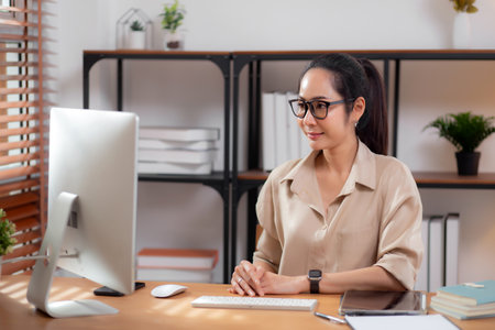 Happiness young businesswoman using desktop computer on desk in living room at home office, business woman using computer for surfing internet, entrepreneur or freelance, business and communication.の写真素材