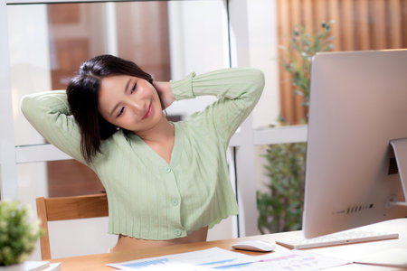 Portrait young asian businesswoman taking a break after overworked with stretching arm and hand in living room at home office, business woman relax with ergonomic, business and health.の写真素材