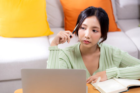 Young asian woman planning and strategy about finance and investment or tax while thoughtful in living room at home, woman with expense and budget while thinking of home, business and finance.の写真素材