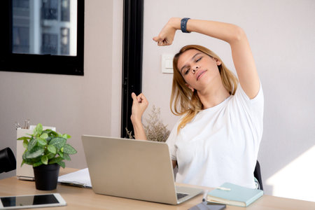 Portrait young caucasian businesswoman taking a break with stretching arm and hand in living room at...