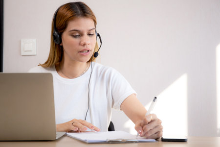 Professional young business woman working and meeting online and writing in modern home office, businesswoman video call with conference distant, call center and support, consulting with business.の写真素材