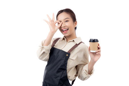 Portrait young asian woman barista holding a takeaway coffee cup with excited gesture ok isolated white background, happy barista presenting takeaway coffee with success, small business or startup.の写真素材