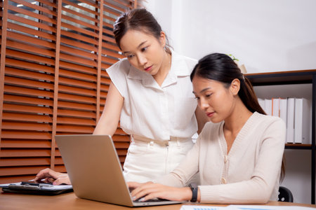 Two young asian businesswoman planning and strategy about marketing and financial with colleagues looking laptop, meeting and working on laptop computer with partner, business and consulting.の写真素材