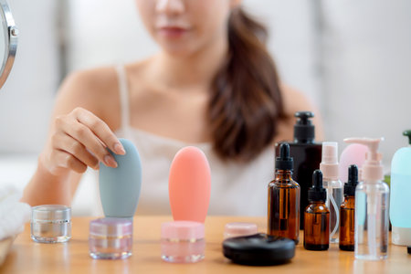 Closeup hands young asian woman cheerful holding skincare or cream at home, beauty woman hold skin care or lotion for rejuvenation on facial, cosmetic and makeup for self care.の写真素材