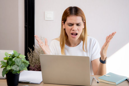 Unhappy young caucasian businesswoman using laptop computer on desk with stress and burnout at home office, business woman working on laptop with frustrated and anxiety, business and expression.の写真素材