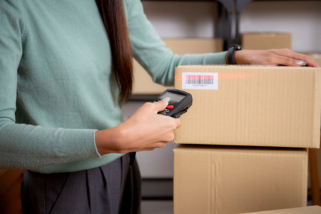 Closeup hand of woman scanning package with barcode reader in office, online seller, shipping and...