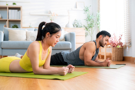 Young asian couple practicing workout with plank while high-five in living room at home, man and woman training exercise for challenge together, motivation and strength of muscle for health.の写真素材