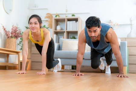 Happy young asian couple workout with doing mountain climbers exercise together in living room at home, smiling and energetic fitness training and cardio routine, motivation for health and wellbeing.の写真素材