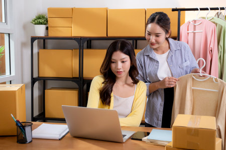 Two young asian businesswoman checking order clothes of customer for laptop computer, shipment and cargo, retail with online seller and store, startup or small business, shipping and inventory.の写真素材