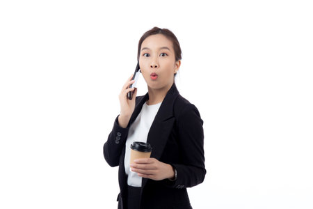 Portrait cheerful young asian businesswoman holding coffee cup while talking smart phone with relax and satisfied isolated white background, business woman drinking coffee and speaking on smartphone.の写真素材
