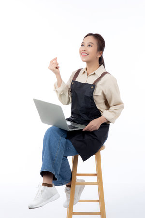 Portrait young asian business woman wearing apron holding laptop computer isolated white background, waitress or barista holding laptop computer with confident, cut out, business or freelance.の写真素材