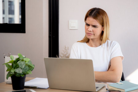 Unhappy young caucasian businesswoman using laptop computer on desk with stress and burnout at home office, business woman working on laptop with frustrated and anxiety, business and expression.の写真素材