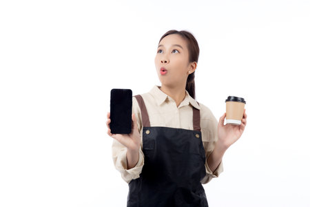 Portrait young asian barista woman wearing apron holding a coffee cup and showing smartphone isolated white background, waitress showing smart phone for order, small business or startup.の写真素材