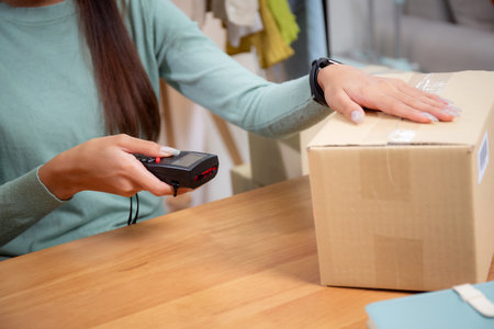 Closeup hand of woman scanning package with barcode reader in office, online seller, shipping and express, distribution and logistic, retail and shipment, business and storage for delivery online.の写真素材