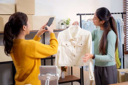 Two asian woman taking picture of clothes for online store, woman collaboration with online seller...