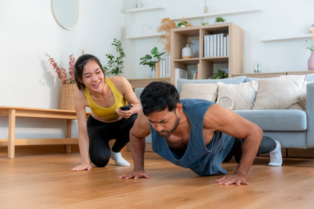 Young asian couple workout during woman hold smartphone encouragement to partner while man doing...