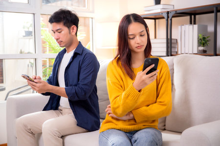 Unhappy asian couple sitting on sofa having relationship problem in living room at home, emotion...