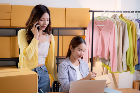 Two asian woman e-commerce startup in home office, two young entrepreneur management order, online seller teamwork, packing product for preparation delivery, retail and shipping, business  concept.の写真素材