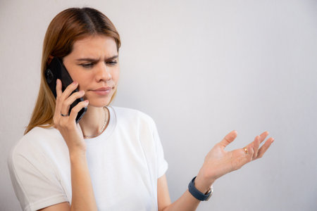 Young caucasian businesswoman working on laptop computer while talking on smartphone with stress and upset in office, business woman talking on smart phone with frustrated, business and expression.の写真素材
