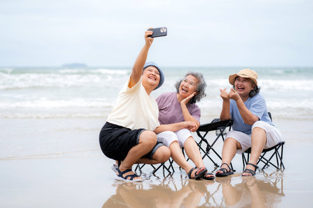 Happy group senior asian woman taking selfie on beach vacation, elderly friend smiling and enjoy...