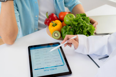 Asian nutritionist using tablet to explaining personalized meal plan with AI to patient during healthcare consultation, healthy lifestyle, woman dietitian showing nutrition plan with AI on tablet.の写真素材