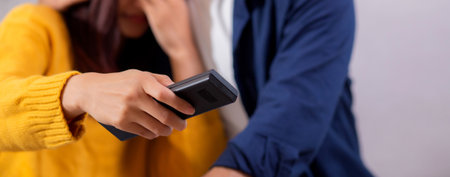 Closeup young asian couple watching a scary or thrilling TV show in living room with emotion shock and scared, emotion reaction while watching horror television with fear, lifestyle and bonding.の写真素材
