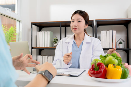 Asian nutritionist consulting patient in clinic, meal plan discussion, healthcare advice, weight loss support, doctor talking and explaining patient for nutrition consultation, wellness care.の写真素材