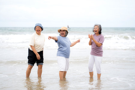 Group senior asian woman laughing and playing together at beach, enjoy vacation with friendship after retirement, cheerful elderly group with fun, relaxation with happiness and carefree in summer.の写真素材