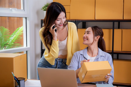 Two asian woman e-commerce startup in home office, two young entrepreneur management order, online seller teamwork, packing product for preparation delivery, retail and shipping, business  concept.の写真素材