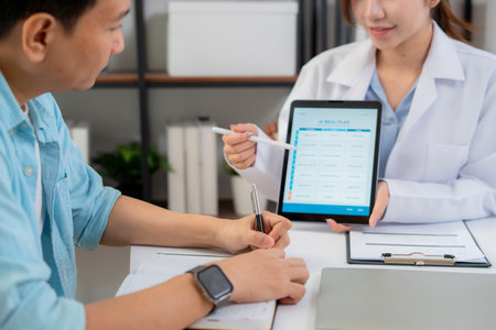 Close up nutritionist using tablet to explaining personalized meal plan with AI to patient during healthcare consultation, healthy lifestyle, woman dietitian showing nutrition plan with AI on tablet.の写真素材