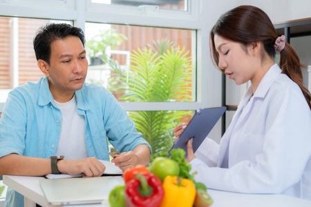 Asian nutritionist using tablet to explaining personalized meal plan with AI to patient during healthcare consultation, healthy lifestyle, woman dietitian showing nutrition plan with AI on tablet.の写真素材