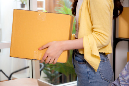 Young asian woman organizing packages for preparing with shipping and delivery, retail with online seller and store, startup or small business, shipping and inventory, e-commerce, woman carrying box.の写真素材