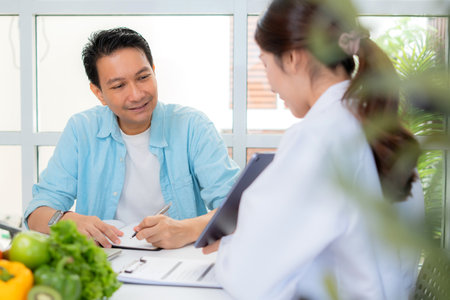 Asian nutritionist using tablet to explaining personalized meal plan with AI to patient during healthcare consultation, healthy lifestyle, woman dietitian showing nutrition plan with AI on tablet.の写真素材