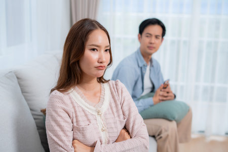 Angry asian couple sitting sofa with conflict and frustrated, woman ignoring boyfriend, toxic relationship problem and argument, stress and tension, feeling disappointed and sad, worried and upset.の写真素材