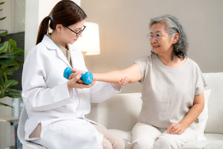 Asian physiotherapist helping senior patient with dumbbell exercise, doctor therapy rehabilitation...