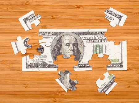 Puzzle of a hundred dollar bill on a wooden backgroundの写真素材