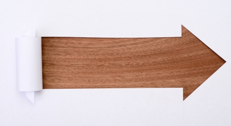 Ripped white paper in the shape of an arrow with space for text with wooden backgroundの写真素材