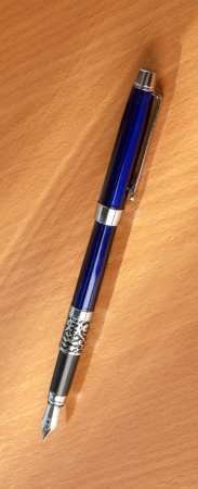 The blue pen on a wooden background