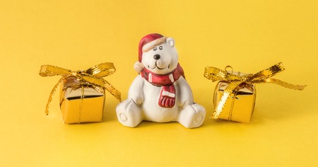 white teddy bear with gifts on a yellow backgroundの写真素材