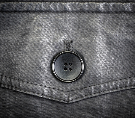 Fragment of black leather jacket with button close-up