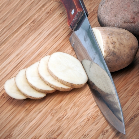 potatoes with a knife on a wooden boardの写真素材