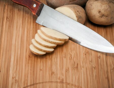 potatoes with a knife on a wooden boardの写真素材