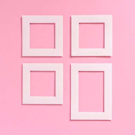 Empty white frames on a pink textured paper background, top view. Flat lay