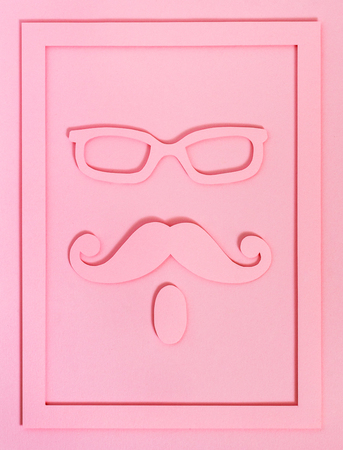 Hipster cut from paper in a frame on a pink textured background, top view. Glasses, mustache and beard. Flat layの写真素材