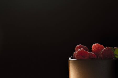 Mug filled with red, ripe raspberries.
